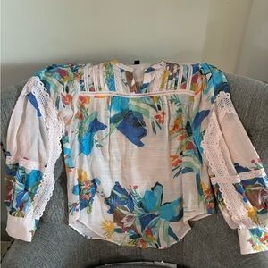 Pale pink blouse with bold flowers and lace overlays.